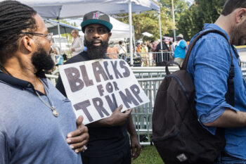 Atlanta, GA / USA - August 24, 2023:  An African-American man holds a sign reading "Blacks for Trump" as he and others gather outside the Fulton County Jail on August 24, 2023 in Atlanta, GA.