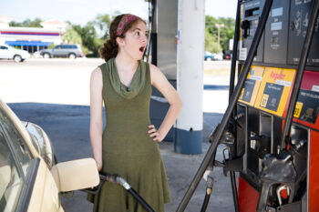 Young woman filling up her gas tank is shocked by the high fuel prices.