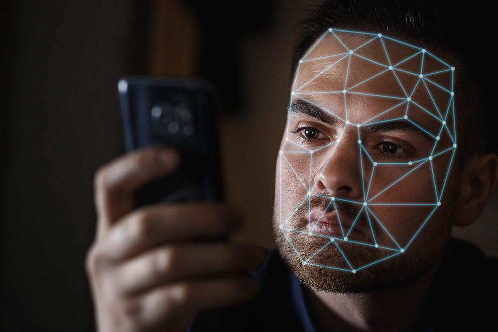 Bearded Man with smartphone using face ID recognition system.